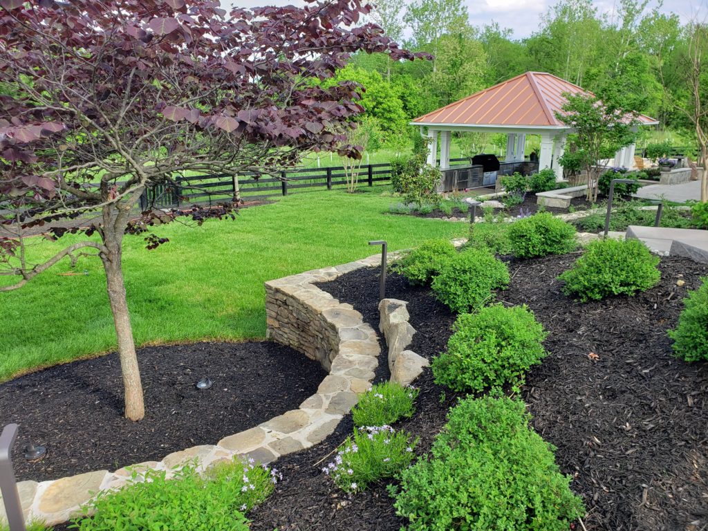 willowsford backyard with forest pansy redbud and fieldstone wall
